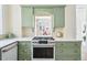 Well-lit kitchen with an oven range, custom green cabinets, and an open pass-through to the dining room at 1368 N Gilpin St, Denver, CO 80218