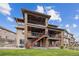 A multi-story home with stone accents, outdoor balconies, stairs to the backyard, and a well-maintained lawn at 16371 Jones Mountain Way, Broomfield, CO 80023