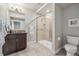 Bathroom featuring a glass enclosed shower, dark vanity, plus neutral tile and stylish fixtures at 16371 Jones Mountain Way, Broomfield, CO 80023