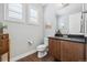 A neutral powder room features a dark countertop, shaker cabinets and two windows at 16371 Jones Mountain Way, Broomfield, CO 80023