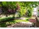 Relaxing backyard with mature trees, stone patio, and lush lawn, perfect for outdoor entertaining at 664 Clarendon Dr, Longmont, CO 80504