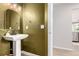 Stylish powder room with a pedestal sink, designer mirror, and green textured walls at 664 Clarendon Dr, Longmont, CO 80504