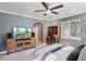 This bedroom features a ceiling fan, large tv, and desk area with a comfortable bed and natural light at 22419 Springflower Dr, Golden, CO 80401