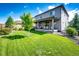 Spacious backyard with lush green grass, mature trees, and covered patio at 350 Vista Cliff Cir, Castle Rock, CO 80104