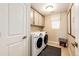 Well-lit laundry room with front-loading washer and dryer, storage cabinets, and tile flooring at 350 Vista Cliff Cir, Castle Rock, CO 80104