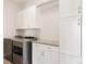 Modern laundry room with stainless steel appliances, white cabinets, and a countertop for folding at 6068 Beeler Ct, Denver, CO 80238