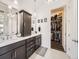 Elegant bathroom featuring dual sinks, dark cabinets, and entry to large closet at 15747 Willow Way, Thornton, CO 80602