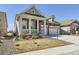 Inviting home with a covered porch, stone accents, well-maintained lawn, and a two-car garage at 15747 Willow Way, Thornton, CO 80602