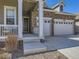 Welcoming home with a covered porch, stone accents, well-maintained lawn, and a two-car garage at 15747 Willow Way, Thornton, CO 80602