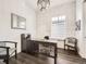 Bright home office featuring a modern chandelier, large window, and sleek wooden desk with ample natural light at 15747 Willow Way, Thornton, CO 80602