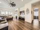 Open living room with hardwood floors, a fireplace, a ceiling fan, and large windows at 15747 Willow Way, Thornton, CO 80602