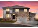 Charming two-story home boasts a stone facade and three-car garage, illuminated by a vibrant sunset at 1965 S Coolidge Way, Aurora, CO 80018