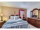 Inviting bedroom with a wooden dresser, nightstand, and a plush bed with blue accents at 4933 Altura St, Denver, CO 80239