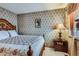 Bedroom with floral wallpaper, a plush bed, wooden nightstand, and soft natural light at 4933 Altura St, Denver, CO 80239