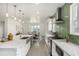 Open kitchen featuring an island with sink, white cabinets, stainless appliances and green tile backsplash at 3350 S Eudora St, Denver, CO 80222