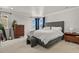 Bright bedroom featuring a gray upholstered bed, blue curtains, and contemporary wood furniture at 5446 Coltin Trl, Castle Rock, CO 80104