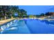 Long swimming pool with submerged lounge chairs and illuminated landscaping at night at 888 S Valentia St # 103, Denver, CO 80247