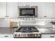 Close-up of a modern stainless steel range under a built-in stainless steel microwave and custom lighting at 4104 N Picadilly Ct, Aurora, CO 80019