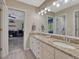 Bathroom featuring a double vanity with granite countertops, a large mirror, and a view into the bedroom at 7672 S Ensenada Ct, Centennial, CO 80016