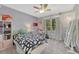 Bright bedroom featuring a colorful ceiling fan, large window, and a view into nature at 7672 S Ensenada Ct, Centennial, CO 80016