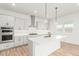 Modern kitchen with white cabinetry, stainless steel appliances, an island with bar seating, and hardwood floors at 1826 Hickory Ave, Erie, CO 80516