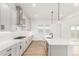Bright kitchen with white cabinets, a stainless steel range hood, and a large island with a sink and stylish pendant lighting at 1826 Hickory Ave, Erie, CO 80516
