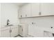 Modern laundry room with white cabinetry, stainless steel sink, and ample counter space at 1826 Hickory Ave, Erie, CO 80516