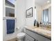 Bright bathroom with granite countertop, grey cabinets, and framed mountain landscape art at 5738 Urban Ctr, Arvada, CO 80002