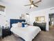 Bright main bedroom featuring a ceiling fan, white walls, and a large bed with a blue headboard and decorative pillows at 5738 Urban Ctr, Arvada, CO 80002