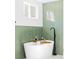 Close up on soaking tub with green herringbone tile surround and minimalist black faucet at 2520 S Race St, Denver, CO 80210