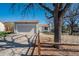 Exterior view of a grey home with a two-car garage, complemented by mature trees and a split-rail fence at 19000 E Mansfield Dr, Aurora, CO 80013