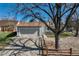 Home featuring a grey exterior, two-car garage, long driveway, mature trees, and a split rail fence at 19000 E Mansfield Dr, Aurora, CO 80013