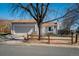Home with grey exterior, two-car garage, front lawn, and beautiful shade tree with a split rail fence at 19000 E Mansfield Dr, Aurora, CO 80013