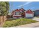 Charming red home featuring well-kept lawn, brick accents, white garage door, and manicured landscaping at 9408 High Cliffe St, Highlands Ranch, CO 80129