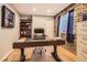 Well-lit home office with a large desk, built-in shelving, and a stone accent wall at 9408 High Cliffe St, Highlands Ranch, CO 80129