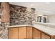 Basement wet bar featuring stone wall, tile counters and wood cabinets at 9408 High Cliffe St, Highlands Ranch, CO 80129