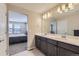 Well-lit bathroom featuring double sinks, a modern vanity, and a glimpse into an adjacent bedroom at 6492 N Ceylon St, Denver, CO 80249