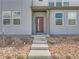 Close-up of a modern townhouse front entrance featuring desert landscaping, concrete steps, and red front door at 6492 N Ceylon St, Denver, CO 80249