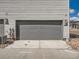 Two car garage with a gray door, exterior lighting, and an easy to maintain yard at 6492 N Ceylon St, Denver, CO 80249