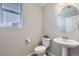 Clean powder room features a pedestal sink, oval mirror, and a window for natural light at 6492 N Ceylon St, Denver, CO 80249