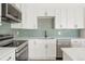 Bright kitchen featuring white cabinetry, stainless steel appliances, and tile backsplash at 6539 Pinewood Dr # 57, Parker, CO 80134