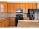 Kitchen boasts warm wood cabinets and black appliances at 15455 Canyon Rim Dr # 307, Englewood, CO 80112