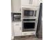 Built-in stainless steel oven and microwave with white cabinets and drawers at 13432 Broad Wing Dr, Parker, CO 80134