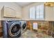 Well-equipped laundry room featuring tile floor, modern washer, dryer and storage at 19070 White Fawn Dr, Monument, CO 80132