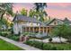 Stunning two-story home with a brick and black metal fence, a beautiful lawn, and a large, inviting wrap-around porch at 3109 E Warren Ave, Denver, CO 80210