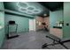 A home gym features an edgy geometric ceiling fixture, dark floors, and trendy green walls at 4465 Mesa Top Dr, Monument, CO 80132