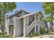 Inviting two-story condo with gray siding, red door, staircase entrance, and fresh green landscaping at 8500 E Jefferson # 3C, Denver, CO 80237