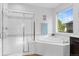 Bright bathroom featuring a soaking tub, walk-in shower, and large window at 13673 Osage St, Broomfield, CO 80023