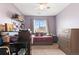 Comfortable bedroom with lilac walls, complete with a desk, large dresser and a ceiling fan at 13673 Osage St, Broomfield, CO 80023