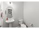 This well-lit powder room features a pedestal sink, round mirror, and crisp, neutral paint, creating a clean and inviting space at 13673 Osage St, Broomfield, CO 80023